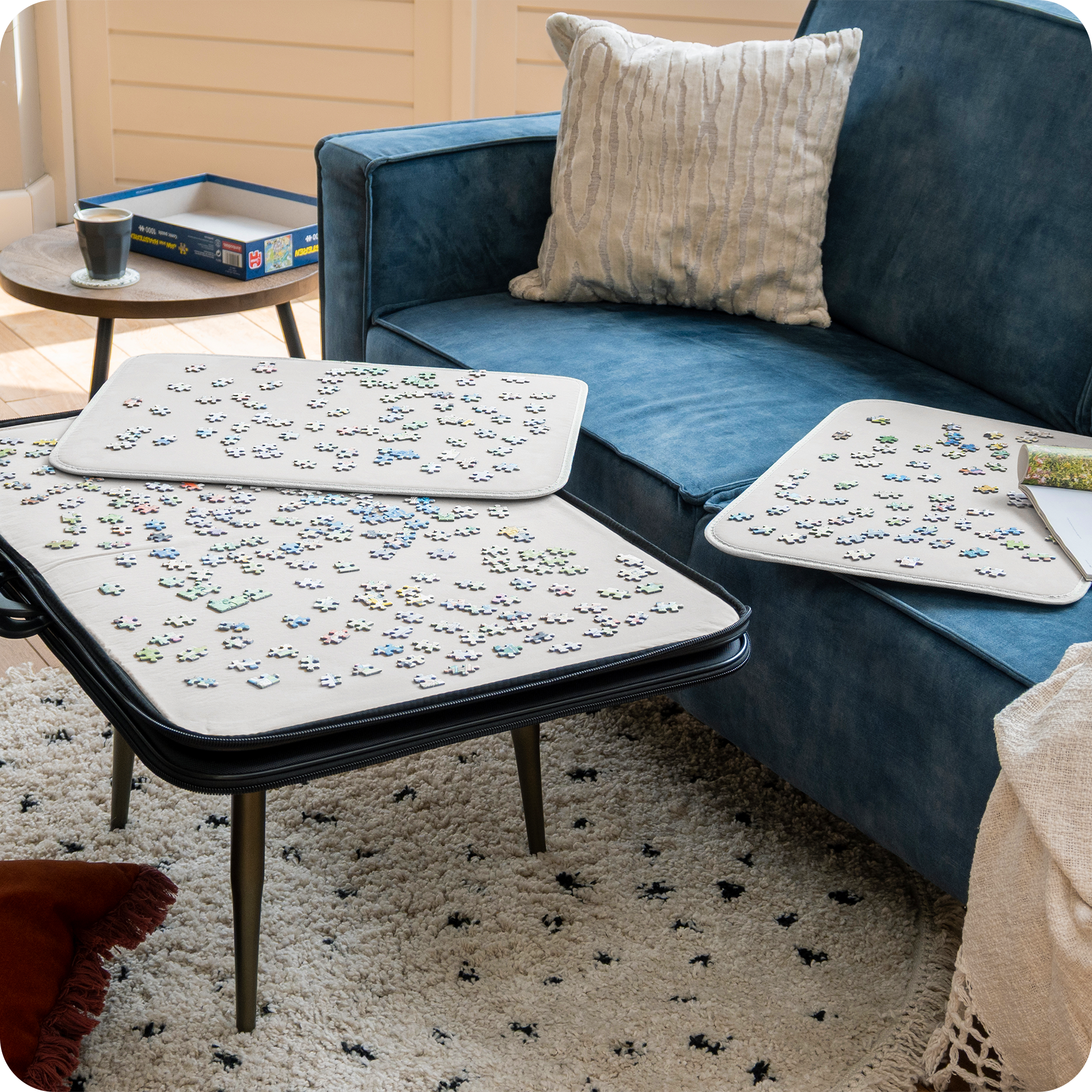 Een moderne woonkamer met een blauwe bank en landelijke decoratie. De puzzelmap ligt op de salontafel waar een puzzel op gemaakt wordt van 1000 stukjes.